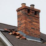 Storm-damaged brick chimney with displaced bricks and impact damage on a residential roof — Spring Hill Chimney Service NEPA